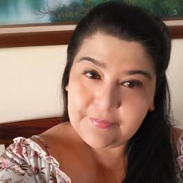 Portrait of a smiling woman with long dark hair wearing a floral blouse