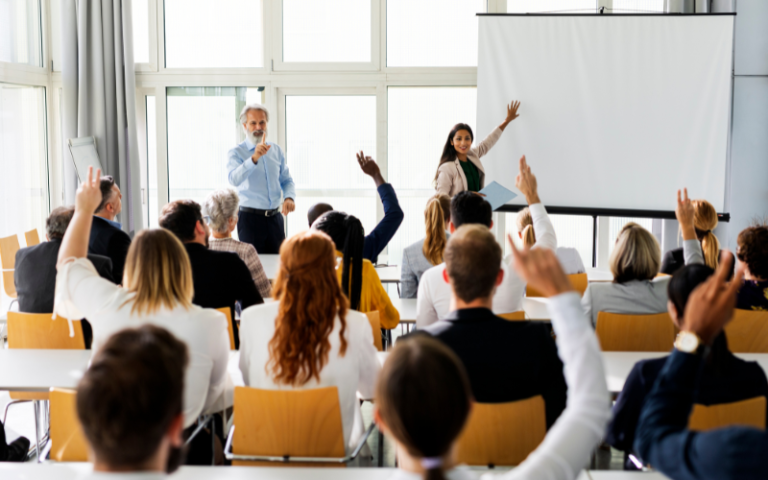 People raising hands in a classroom