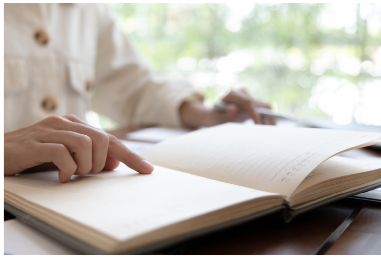 A person reading a notebook, only hands are visible on the notebook
